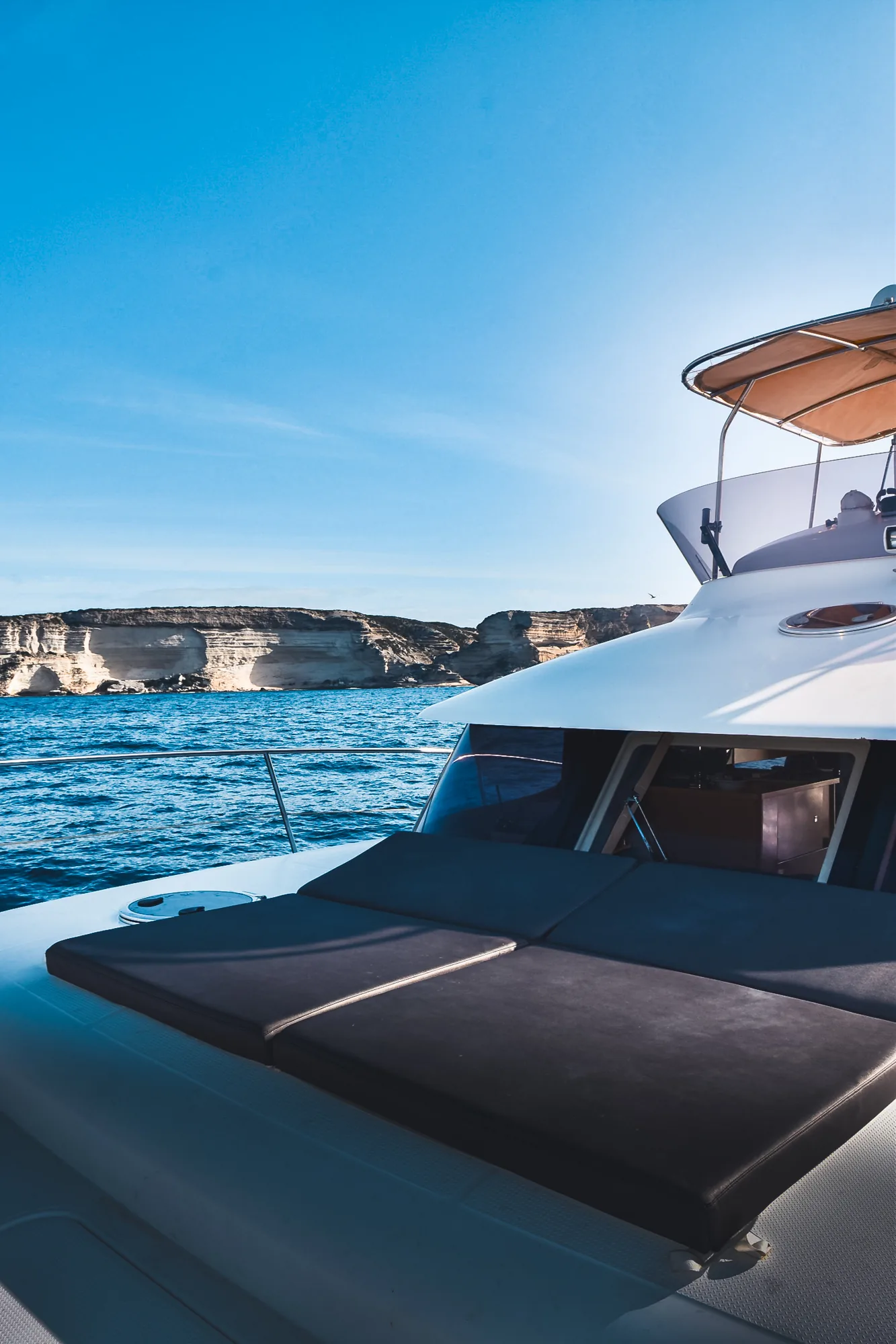 Vue artistique du catamaran Maora devant les falaises de Bonifacio